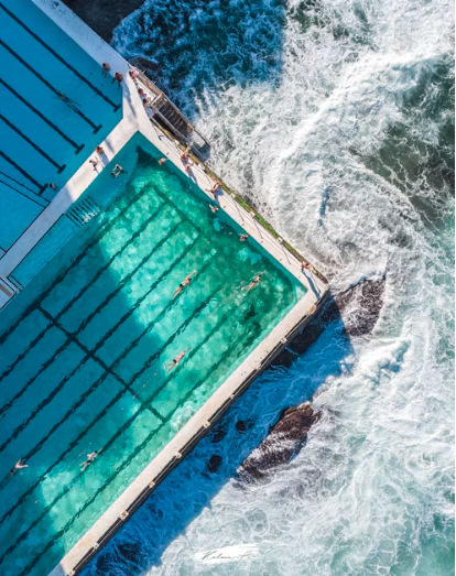 Aerial view of the Bondi Icebergs ocean pool with swimmers doing laps beside breaking surf
