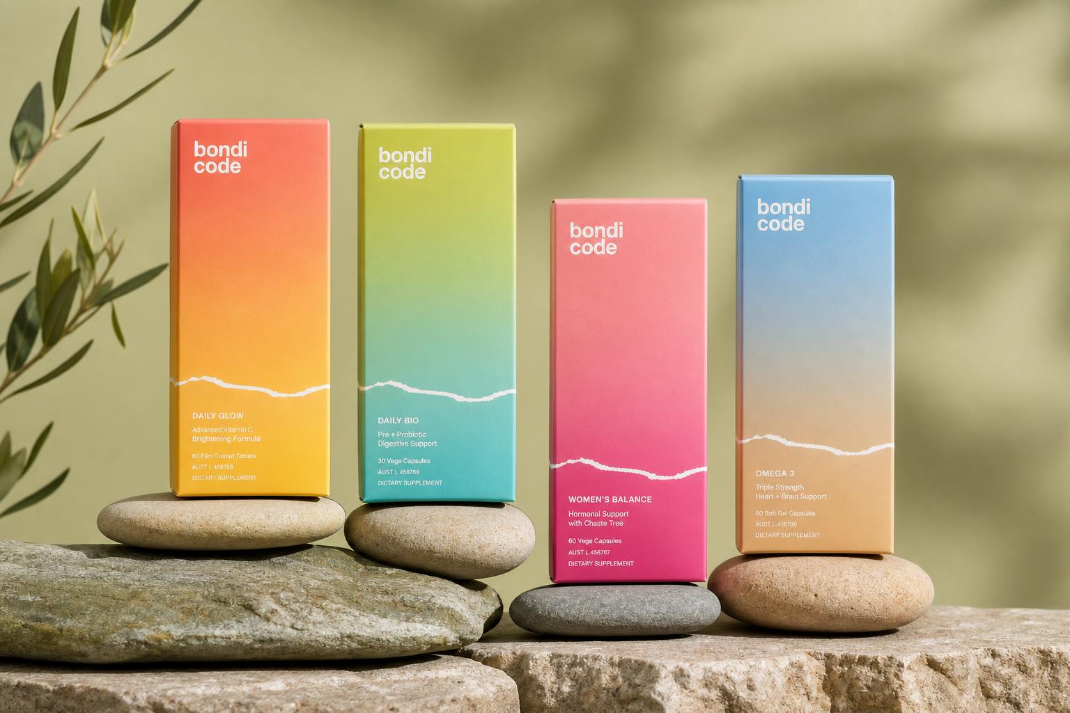 Four Bondi Code protocol cartons in gradient colourways of coral, lime, pink and sky blue, standing on stacked river stones against a warm olive backdrop